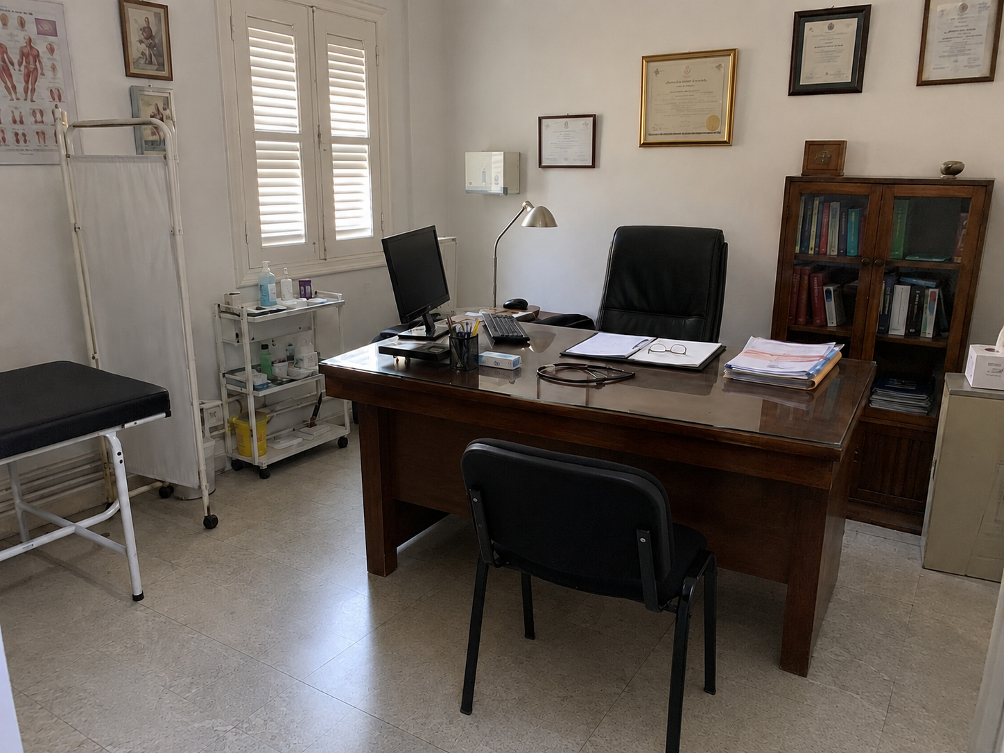 Consultation office in the clinic: doctor's table and examination bed behind a screen